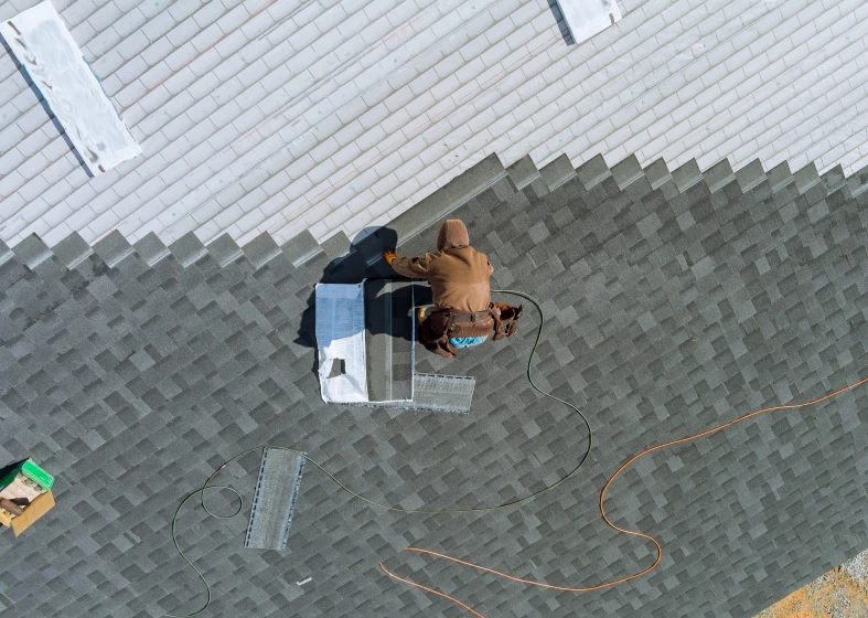 Roofer working on shingled rooftop